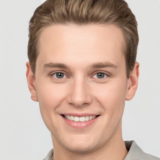 Joyful white young-adult male with short  brown hair and grey eyes