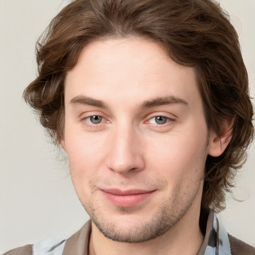 Joyful white young-adult male with medium  brown hair and grey eyes