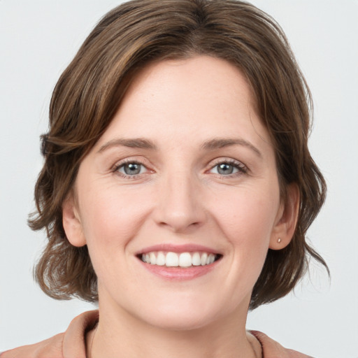 Joyful white young-adult female with medium  brown hair and grey eyes