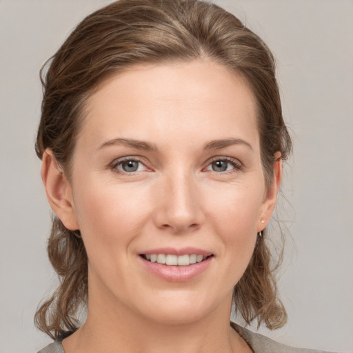 Joyful white young-adult female with medium  brown hair and grey eyes