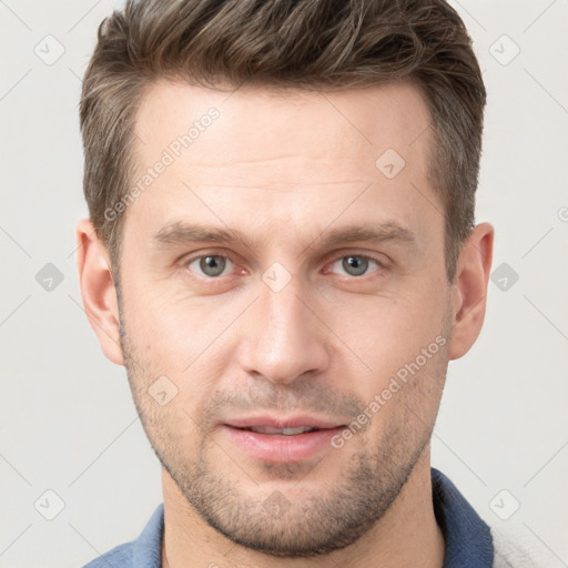 Joyful white young-adult male with short  brown hair and grey eyes