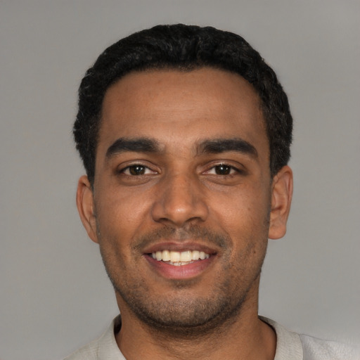 Joyful black young-adult male with short  black hair and brown eyes