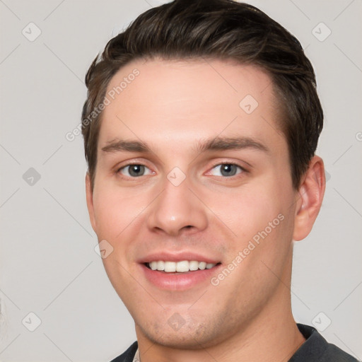 Joyful white young-adult male with short  brown hair and grey eyes