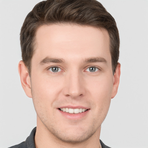 Joyful white young-adult male with short  brown hair and grey eyes