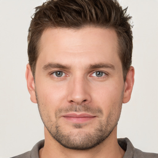 Joyful white young-adult male with short  brown hair and grey eyes