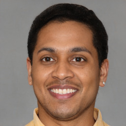 Joyful latino young-adult male with short  brown hair and brown eyes