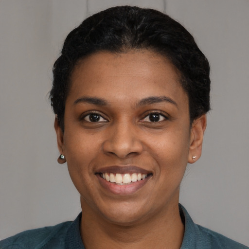 Joyful black young-adult female with short  black hair and brown eyes