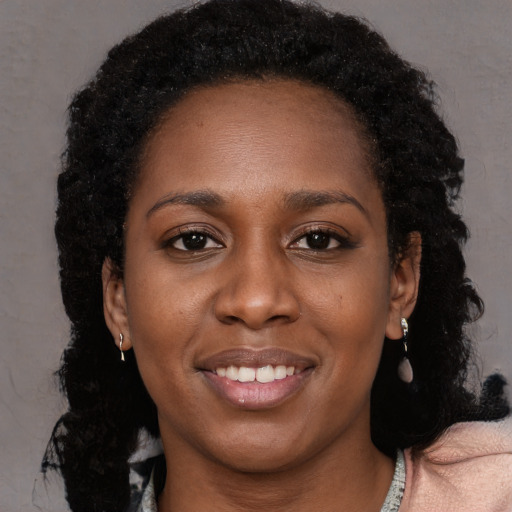 Joyful black young-adult female with long  brown hair and brown eyes