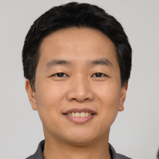Joyful asian young-adult male with short  black hair and brown eyes