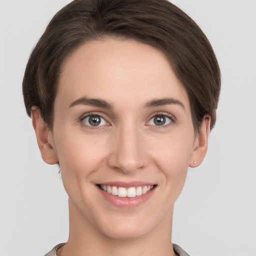 Joyful white young-adult female with short  brown hair and grey eyes