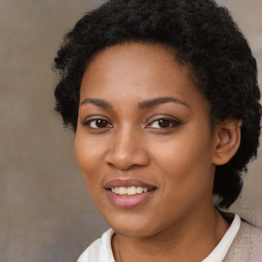 Joyful black young-adult female with short  black hair and brown eyes