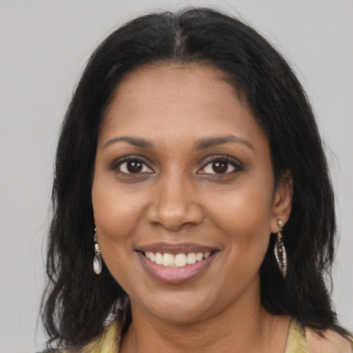 Joyful black young-adult female with long  brown hair and brown eyes