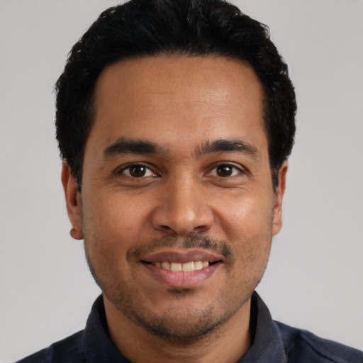 Joyful latino young-adult male with short  black hair and brown eyes