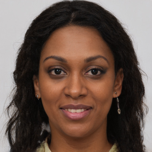 Joyful black young-adult female with long  brown hair and brown eyes