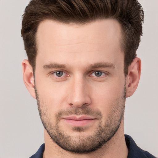 Joyful white young-adult male with short  brown hair and grey eyes