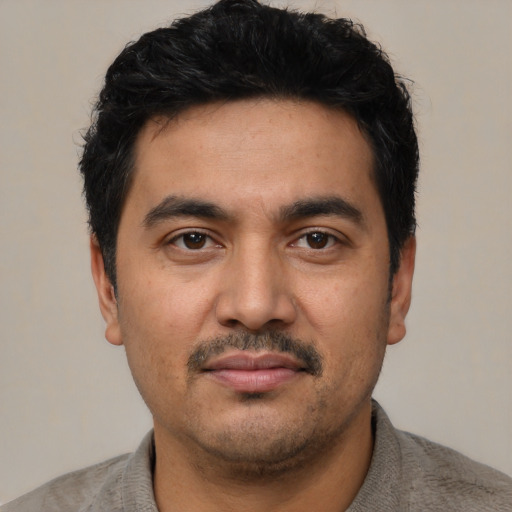 Joyful latino young-adult male with short  black hair and brown eyes