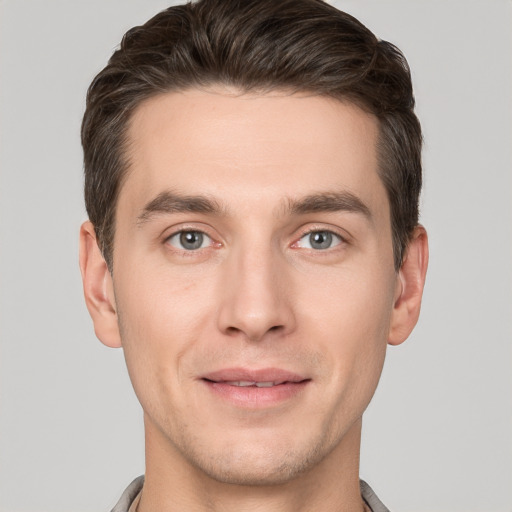 Joyful white young-adult male with short  brown hair and grey eyes