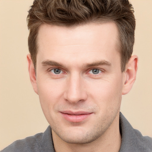 Joyful white young-adult male with short  brown hair and grey eyes