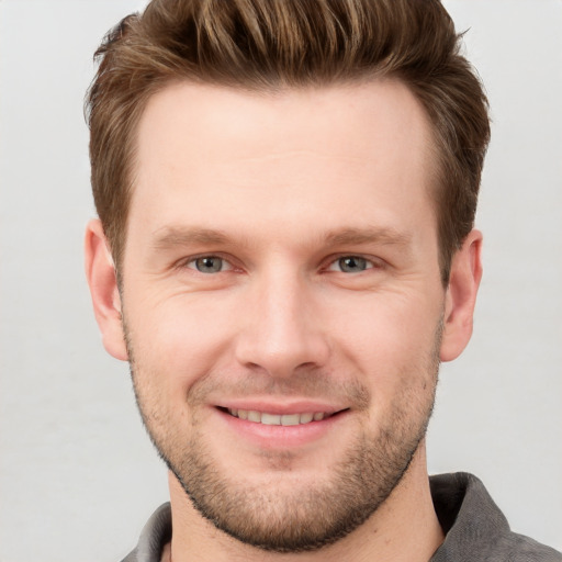 Joyful white young-adult male with short  brown hair and grey eyes