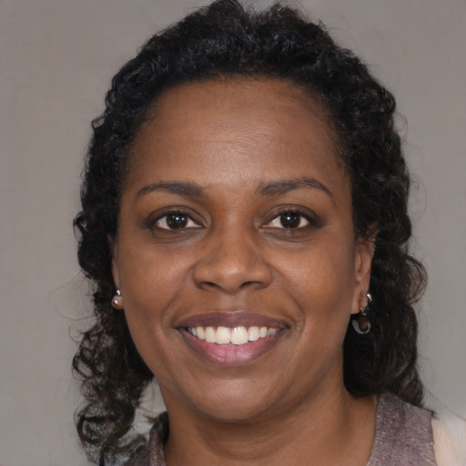 Joyful black adult female with long  brown hair and brown eyes