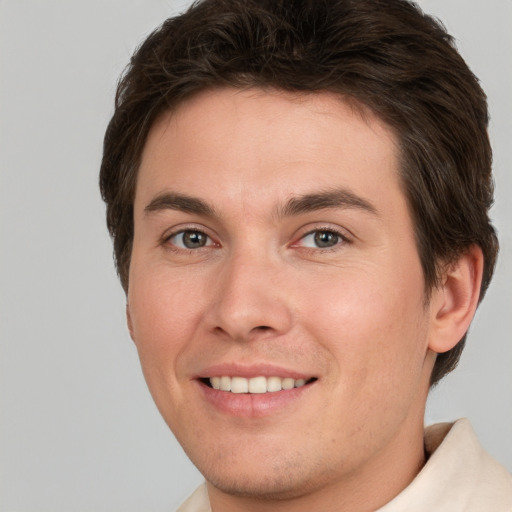 Joyful white young-adult male with short  brown hair and grey eyes