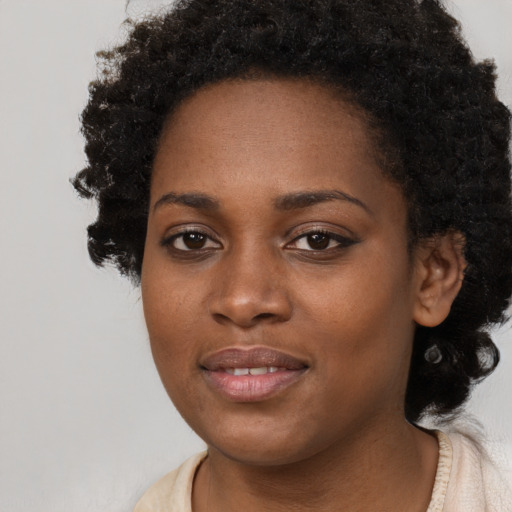 Joyful black young-adult female with long  black hair and brown eyes