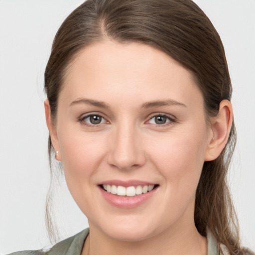 Joyful white young-adult female with medium  brown hair and grey eyes