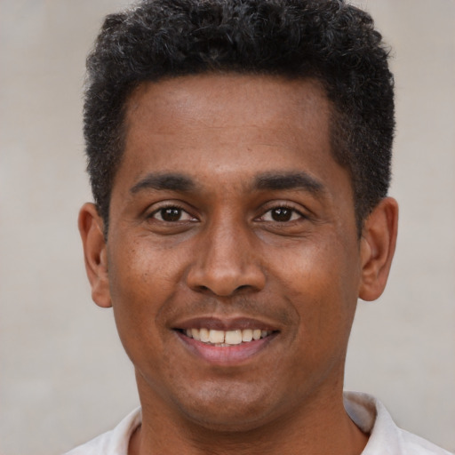 Joyful black young-adult male with short  brown hair and brown eyes