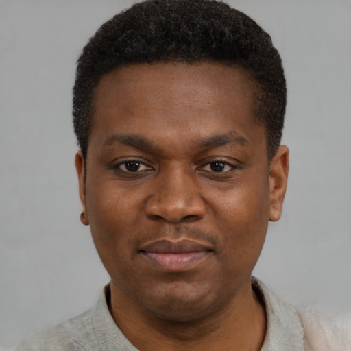 Joyful black young-adult male with short  black hair and brown eyes