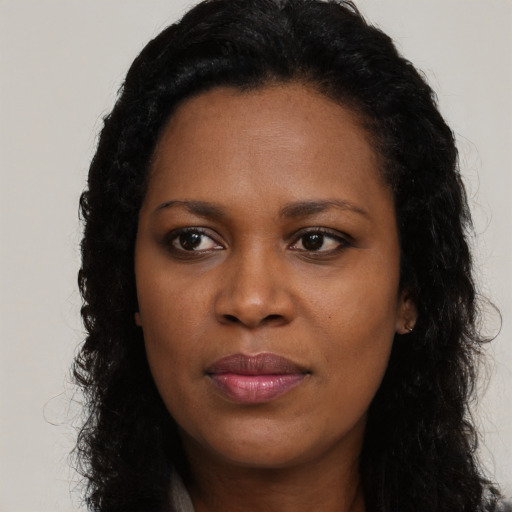 Joyful black young-adult female with long  brown hair and brown eyes