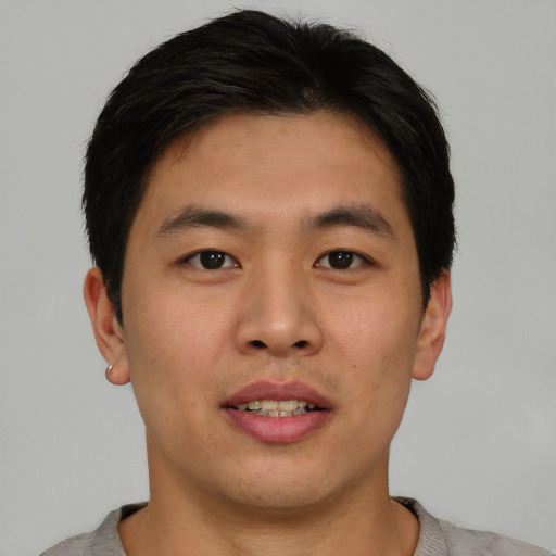 Joyful asian young-adult male with short  brown hair and brown eyes