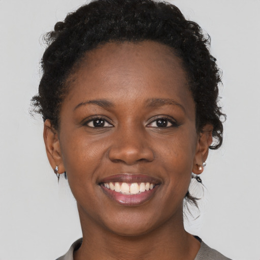 Joyful black young-adult female with short  brown hair and brown eyes