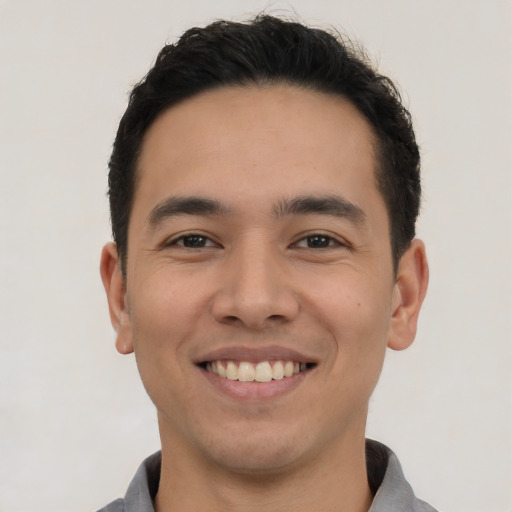 Joyful latino young-adult male with short  black hair and brown eyes