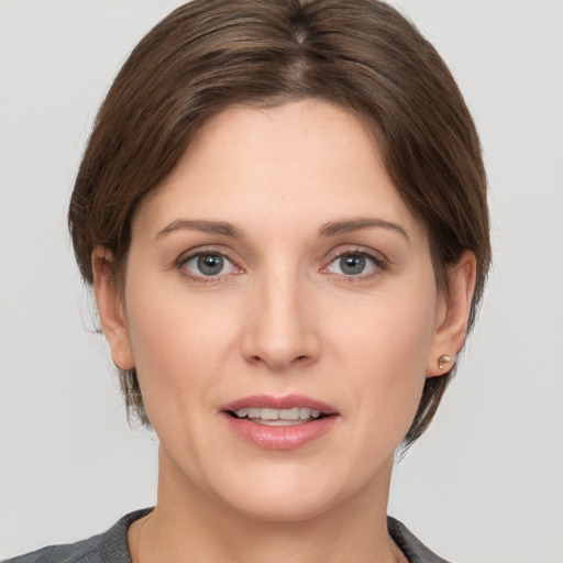 Joyful white young-adult female with medium  brown hair and grey eyes