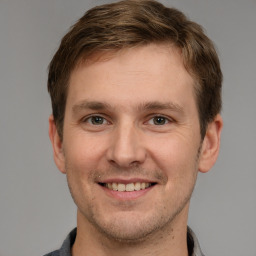 Joyful white young-adult male with short  brown hair and grey eyes