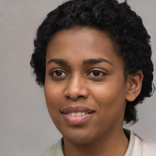 Joyful black young-adult female with short  black hair and brown eyes