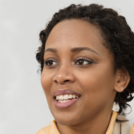 Joyful black young-adult female with long  brown hair and brown eyes