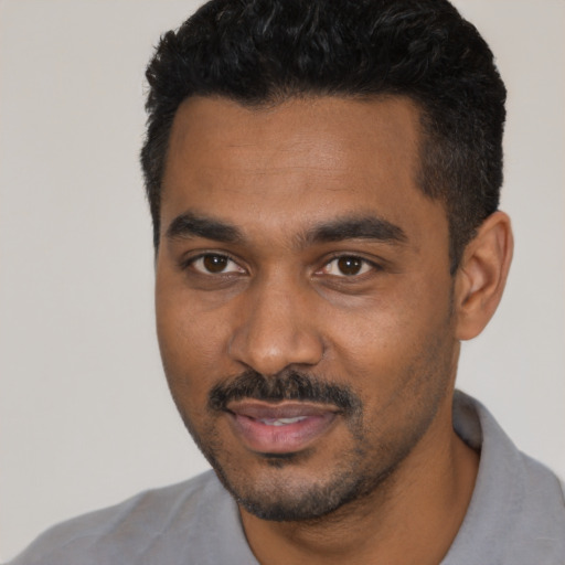 Joyful black young-adult male with short  black hair and brown eyes