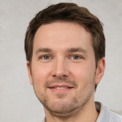 Joyful white young-adult male with short  brown hair and grey eyes