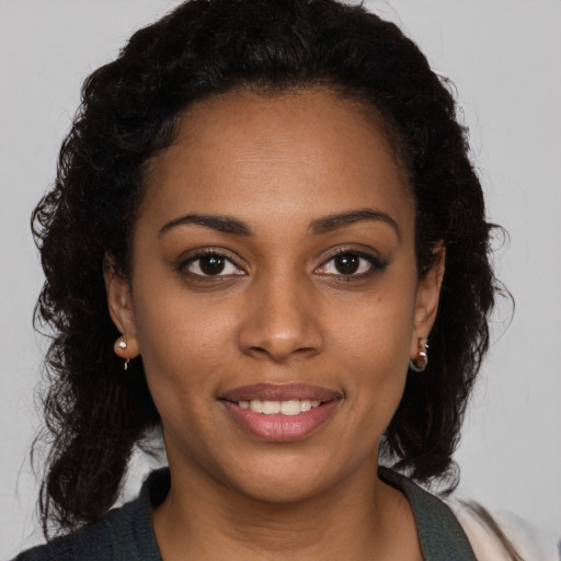 Joyful black young-adult female with long  brown hair and brown eyes