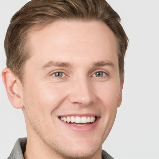 Joyful white young-adult male with short  brown hair and grey eyes