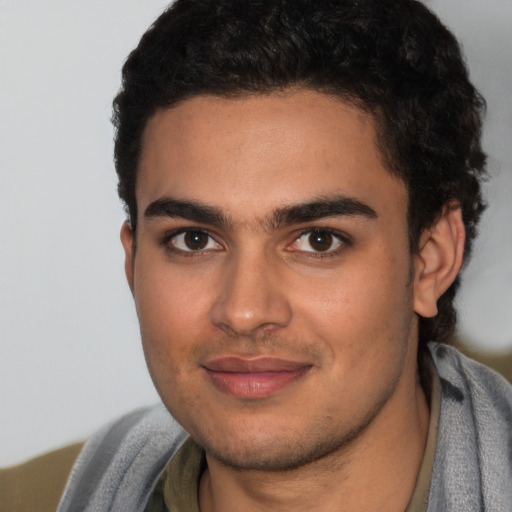 Joyful latino young-adult male with short  brown hair and brown eyes