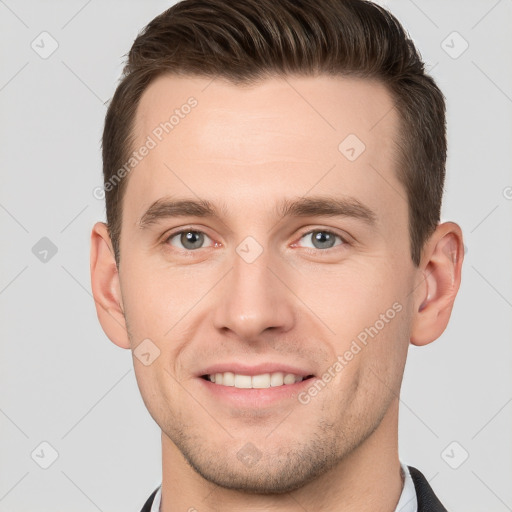 Joyful white young-adult male with short  brown hair and grey eyes