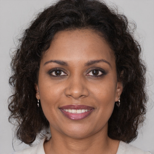 Joyful black adult female with long  brown hair and brown eyes