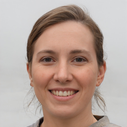 Joyful white young-adult female with medium  brown hair and grey eyes