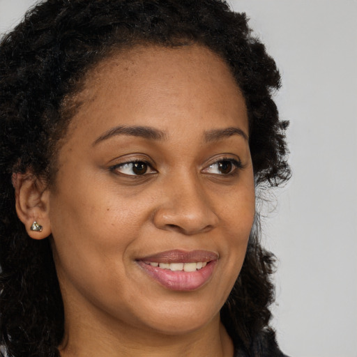 Joyful black young-adult female with long  brown hair and brown eyes