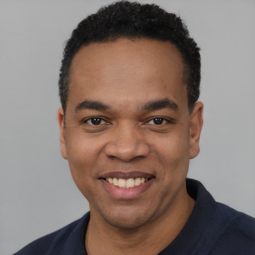 Joyful black young-adult male with short  black hair and brown eyes