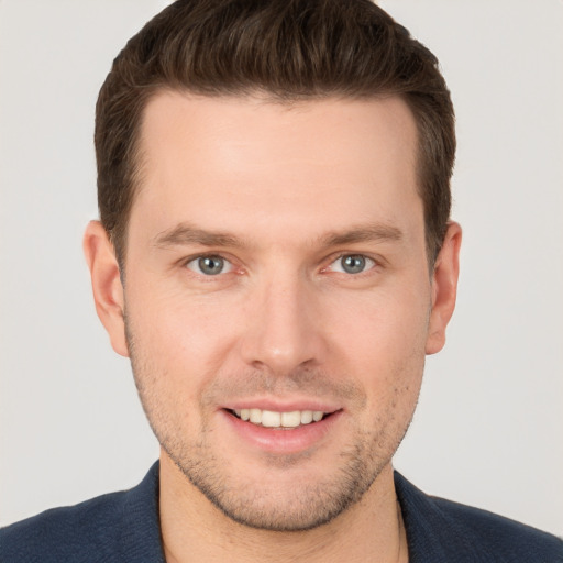 Joyful white young-adult male with short  brown hair and grey eyes