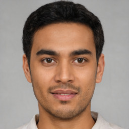 Joyful latino young-adult male with short  black hair and brown eyes