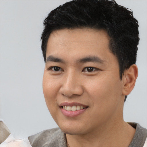 Joyful asian young-adult male with short  black hair and brown eyes